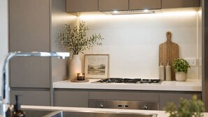 A modern kitchen with a gas stove, a sink, and a countertop with a vase of greenery.