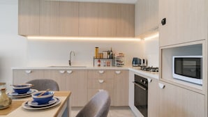 Et moderne køkken med indbygget ovn, mikroovn og vask.