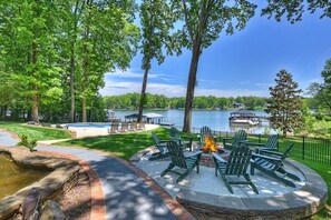 Ein Garten mit Feuerstelle, Sitzgelegenheit im Freien, Schwimmbecken und Blick auf einen See und eine Anlegestelle.