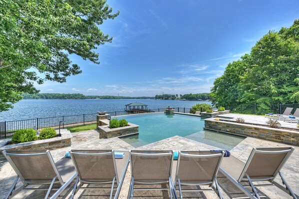 Une piscine avec des chaises longues, un belvédère et une vue sur un lac.