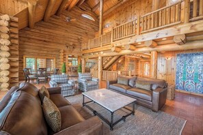 Interior d'una cabana de fusta amb zona d'estar que compta amb sofàs, una taula de centre i una escala.