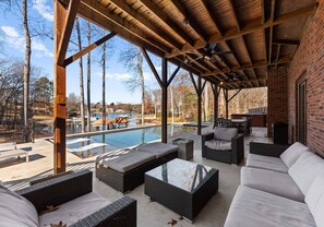 Un patio al aire libre con mobiliario de mimbre, una piscina y vistas a una zona residencial.