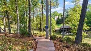 A wooden pathway leading to a pond surrounded by trees. - Lakeside Landing | Game Room | Sleeps 16 (Mooresville)