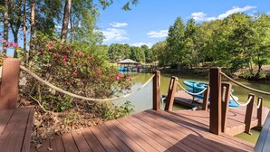 A wooden dock with a rope barrier, a small boat docked, and a gazebo in the background. - Lakeside Landing | Game Room | Sleeps 16 (Mooresville)
