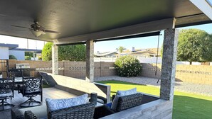 Un patio coperto con arredi da esterno, una ventola a soffitto e vista sul giardino.