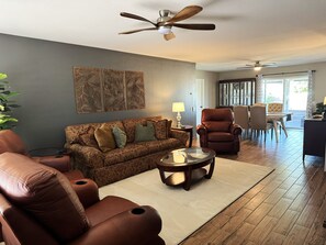 Ein Wohnzimmer mit einer Couch, Sesseln, einem Couchtisch und einem Essbereich mit Stühlen und einem Tisch.
