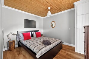 A bedroom with a bed, a bedside lamp, a mirror, and a wardrobe.
