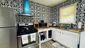 A kitchen with a stainless steel refrigerator, a stove, a microwave, and white cabinets.