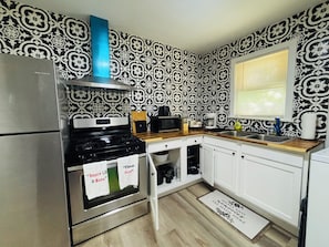 A kitchen with a stainless steel refrigerator, a stove, a microwave, and white cabinets. - Cozy 2BR Retreat • TVs in Every Room • Streaming Included (Shreveport)