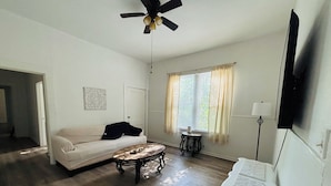 A living room with a sofa, coffee table, and a ceiling fan.