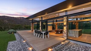 Een modern huis met een terras, buitenmeubels en grote ramen.