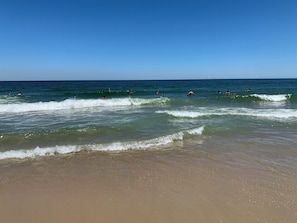 Ein Strand mit Wellen und badenden Personen.