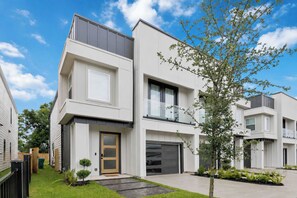 A modern two-story house with a garage, a small front yard, and a tree. - Bassett Bliss / 8m to NRG/FIFA/World Cup Luxe 4BR w/ 1G Fiber & EV (Houston)