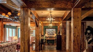 A wooden interior with a chandelier, a fireplace, and a painting on the wall. - Private Sun Valley Lodge | Walk to Lift + Hot Tub (Ketchum)