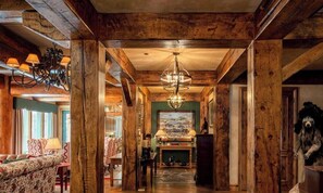 A wooden interior with a chandelier, a fireplace, and a painting on the wall.