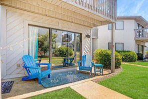 A modern building with a glass door entrance, outdoor seating with blue chairs, and a well-maintained lawn. - Sandy Solstice 5A-Beachside Condo-Sleeps 6 (Destin)