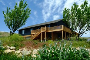 Une maison moderne dotée d’une terrasse en bois, d’un escalier et d’une grande fenêtre.