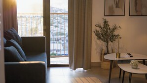 En stue med en sofa, et lille bord, en potteplante og udsigt gennem et vindue.