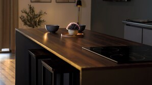 Et moderne køkken med en central ø, barstole, et fladskærms TV og billedkunst på væggene.