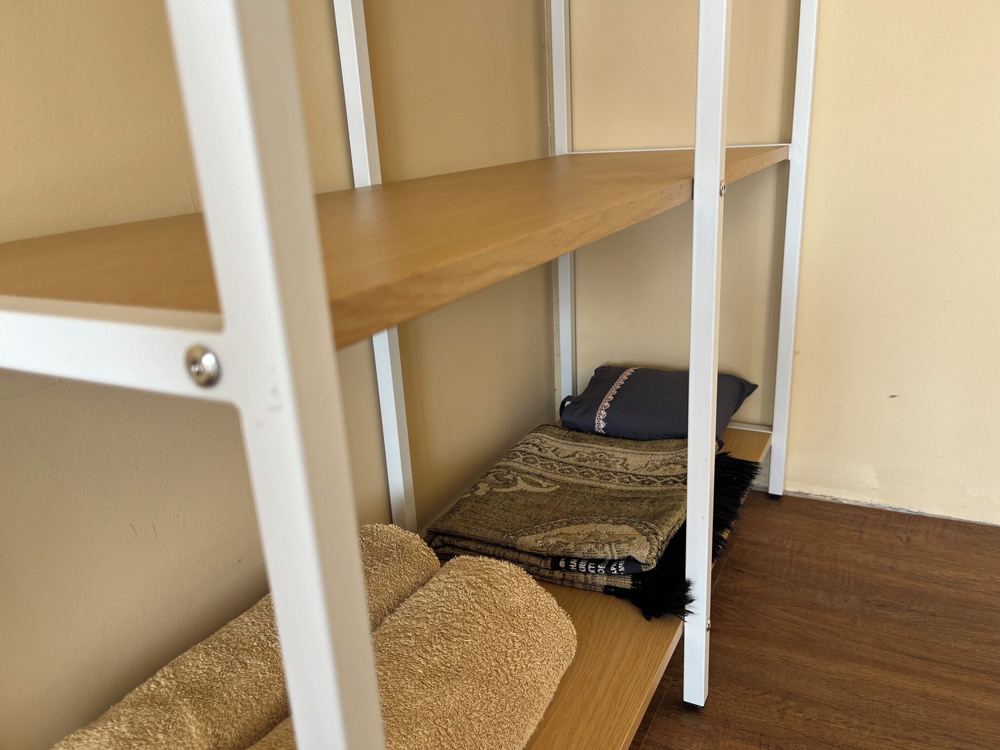 Un lit superposé avec une étagère en bois, une couverture à motifs et un oreiller.
