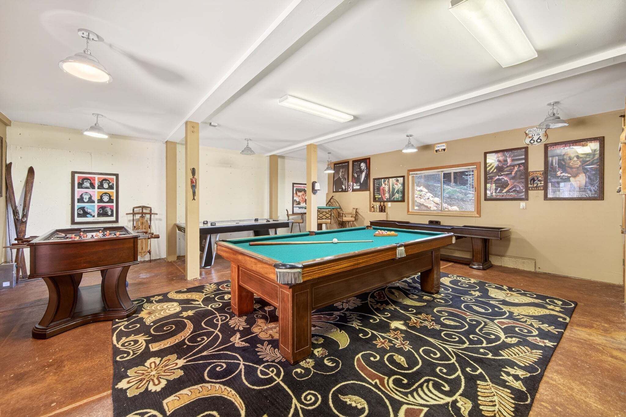 Een pooltafel in een kamer met een kamerbreed tapijt, inbouwspots en ingelijste foto’s aan de muren.