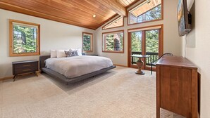 Ein Schlafzimmer mit einem großen Bett, einem Schreibtisch und mehreren Fenstern.