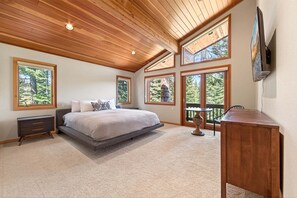 Ein Schlafzimmer mit einem großen Bett, einem Schreibtisch und mehreren Fenstern.