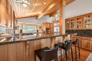 Eine moderne Küche mit Holzausziehtüren, einer Granit-Arbeitsplatte und Barhocker.