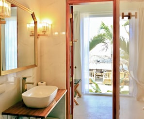 Un baño con un espejo grande, un lavamanos blanco y un mueble de tocador de madera.