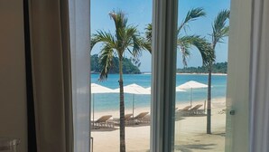 A room with a view of a beach, including palm trees and umbrellas.