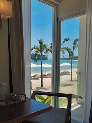Habitación con vista a una playa, incluyendo palmeras y sombrillas.