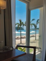 Habitación con vista a una playa, incluyendo palmeras y sombrillas.