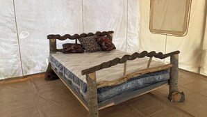 A bed with a wooden frame and a mattress inside a tent-like structure. - Off-Grid Glamping Retreat | 180 Private Acres (Lenoir)