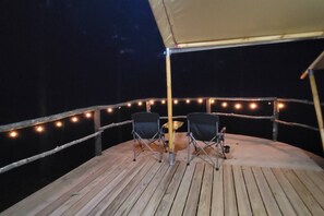 An outdoor deck with two chairs and string lights.