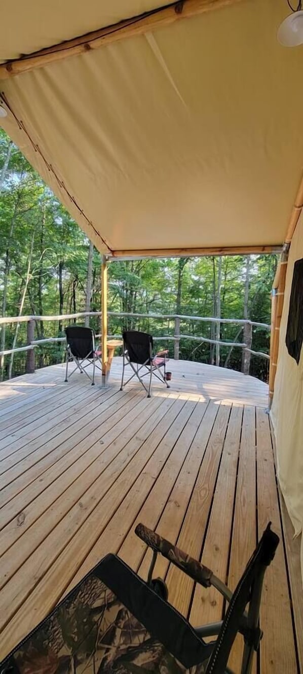 A wooden deck with two chairs and a table, surrounded by a bamboo structure.