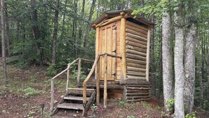 Una cabaña de madera con una escalera que lleva a una puerta, rodeada de un bosque.