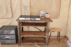 Un bureau en bois rustique, équipé d’un téléviseur à écran plat, d’une machine à café et d’un grille-pain. Il y a des étagères en dessous et une petite table sur le côté.