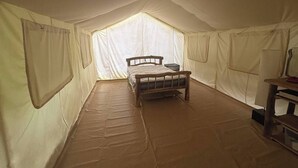 Una tienda de campaña con cama, una mesa y una ventana.