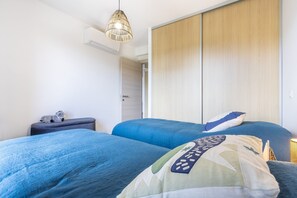 Et soveværelse med to senge, et natbord, en lampe og et garderobeskab.