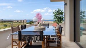 A balcony with a glass table and chairs, a potted plant, and a view of the sea. - Fiore di Macchja - À 5 min à pied de la plage (Albitreccia)