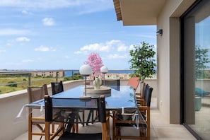 A balcony with a glass table and chairs, a potted plant, and a view of the sea. - Fiore di Macchja - À 5 min à pied de la plage (Albitreccia)