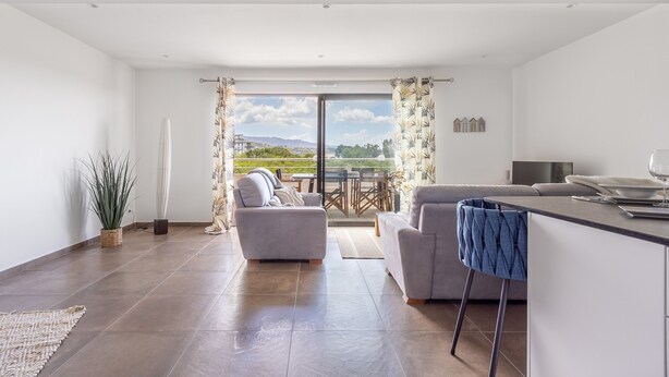 A modern living room with a sofa, a coffee table, and a dining area with a table and chairs. - Fiore di Macchja - À 5 min à pied de la plage (Albitreccia)