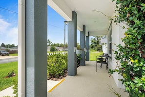 A covered outdoor area with columns, potted plants, and a seating area.