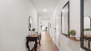 A hallway with a wooden floor, white walls, and a mirror on the right. - Spacious Modern Villa with Private Yard, Ocala (Ocala)