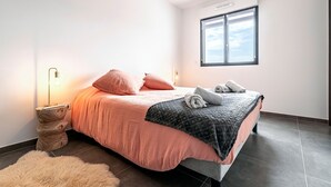 A modern bedroom with a bed, bedside lamp, and a view of the sky through a window. - Luminella - Avec vue sur la mer (Ajaccio)