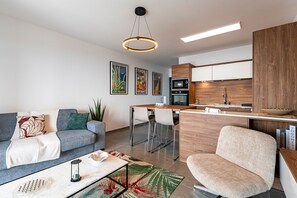 Ein modernes Wohnzimmer mit Sofa, Couchtisch und einer Küchenzeile mit Bar.