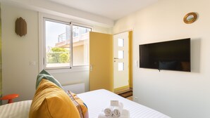 A hotel room with a bed, a TV, a window, and a door leading to a balcony. - Da Viken - Accès direct à la plage (Dinard)