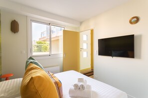 Ein Hotelzimmer mit Bett, Fernseher, Fenster und einer Tür, die auf einen Balkon führt.