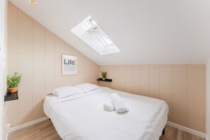 A bedroom with a skylight, a bed with white linens, a small plant on a shelf, and a framed picture on the wall. - Le Laennec - Au centre-ville de Nantes (Nantes)