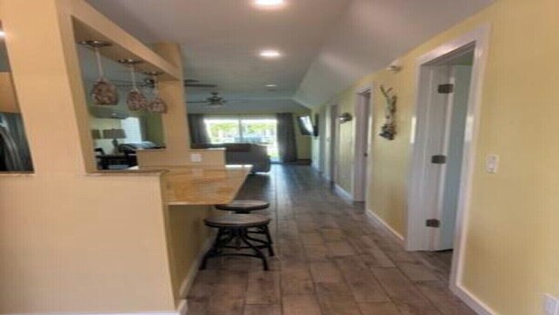 A hallway with a kitchen area, wooden flooring, and a ceiling fan. - Paradise Primo Lower  (Fort Myers Beach)